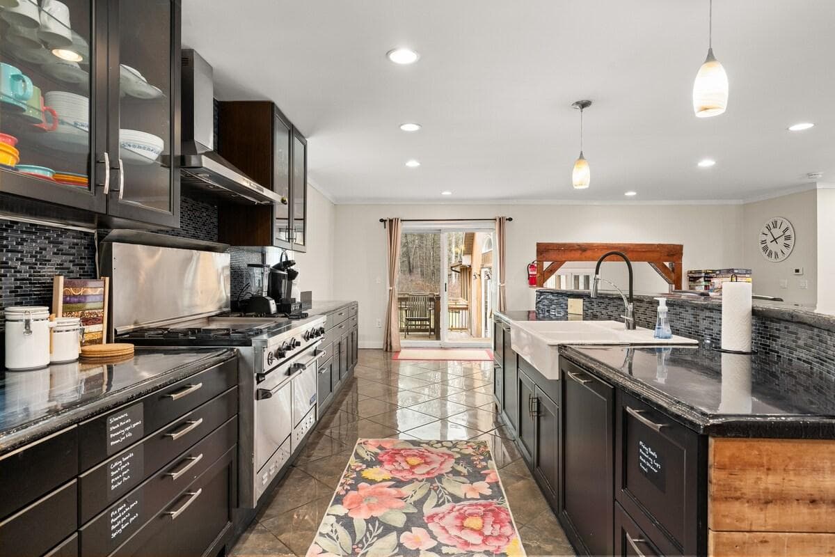 Kitchen features ample counterspace and cabinets, 4-burner gas stove plus griddle, farmhouse sink. Walkout to the primary deck.
